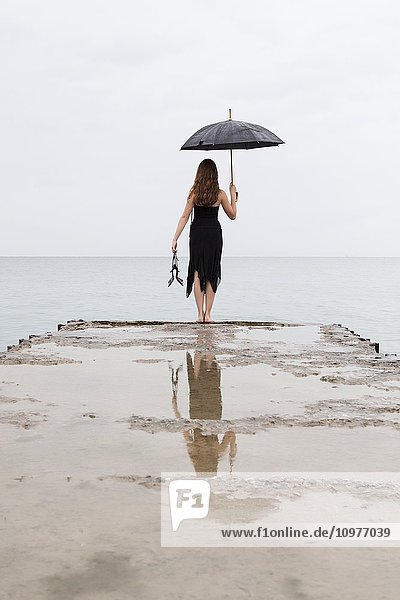 Mädchen steht am Ende eines Piers und hält einen Regenschirm; Toronto  Ontario  Kanada'.