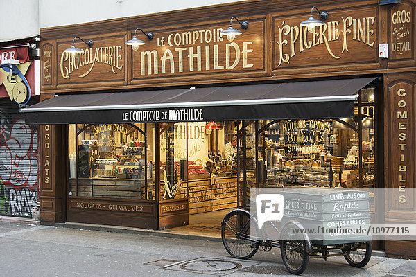 'The richly decorated facade of a traditional chocolate store with antique delivery cart in front; Paris  France'