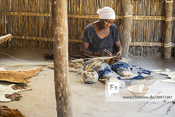 Frau im Dorf Sexaxa bei der Herstellung handgefertigter Schalen; Maun  Botswana'.