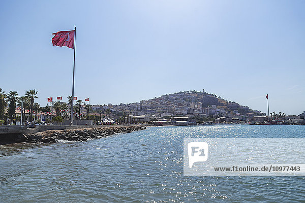 Die türkische Flagge weht in einem blauen Himmel an einem sonnigen Tag am Mittelmeer; Kusadasi  Izmir  Türkei'.