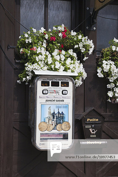Briefkasten und Souvenirmünzautomat an einer Holzwand mit Blumen; Kotna Hora  Tschechische Republik'.