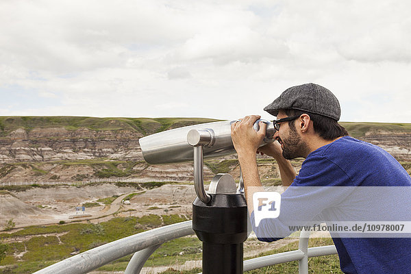 'Man looking through binoculars outdoors at the Royal Tyrell Museum Of Palaeontology; Drumheller  Alberta  Canada'