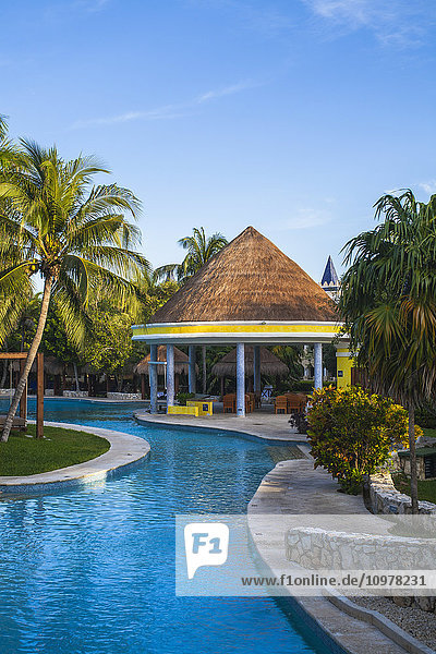 Schwimmbad und strohgedeckter Unterstand in einem Resort an der Karibik; Playa del Carmen  Quintana Roo  Mexiko'.