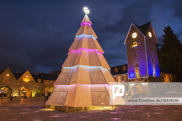 'Tall Christmas tree on a town plaza on a dark cloudy night; Bariloche  Argentina'