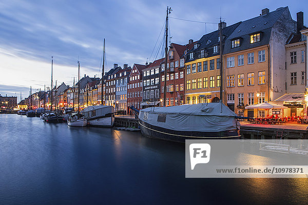 'Nyhavn  the famous waterfront canal in Copenhagen with colourful seventeenth and eighteenth century townhomes lining the canal at dusk; Copenhagen  Denmark'