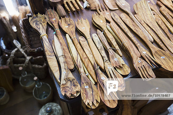 Eine Sammlung handgefertigter Salatbestecke aus Holz liegt auf einem Verkaufstisch in einem Touristengeschäft; Pisa  Siena  Italien'.