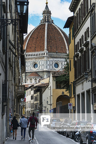 Fußgänger auf einer Straße mit der Kuppel der Kathedrale von Florenz; Florenz  Italien'.