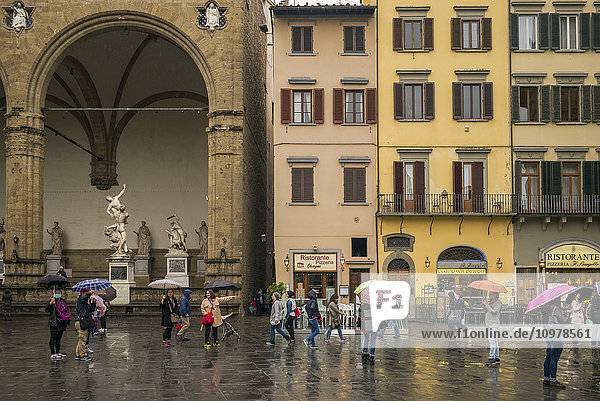 Fußgänger auf einem Stadtplatz an einem regnerischen Tag; Florenz  Italien'.