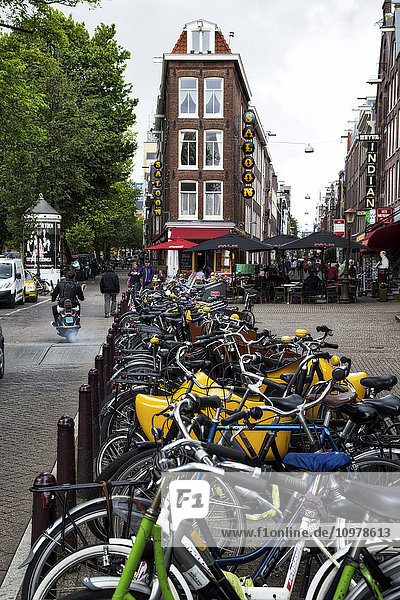 Zahlreiche Fahrräder in einer Reihe entlang einer Straße; Amsterdam  Niederlande'.