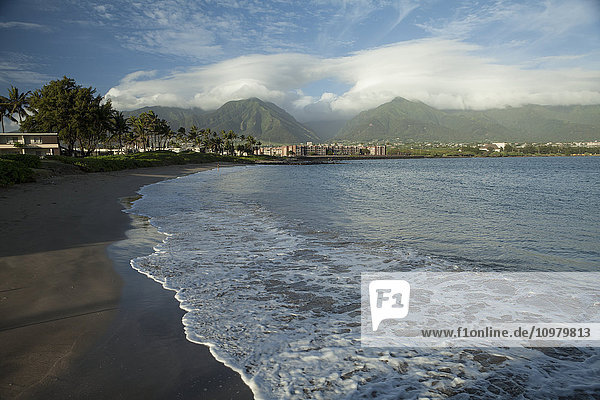 Schwarzer Sandstrand  Eigentumswohnungen und Hotels  Amala Beach  mit Iao Valley im Hintergrund; Kahalui  Maui  Hawaii  Vereinigte Staaten von Amerika'.