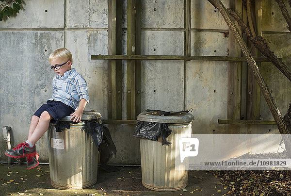 Ein fünfjähriger Junge sitzt auf einer Metallmülltonne im JC Raulston Arboretum; Raleigh  North Carolina  USA'.