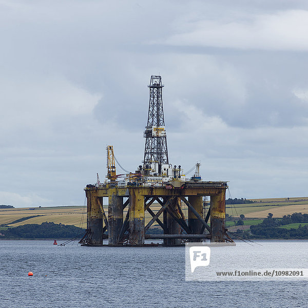 'Drilling rig off the coast with farmland in the background; Invergorden  Scotland'