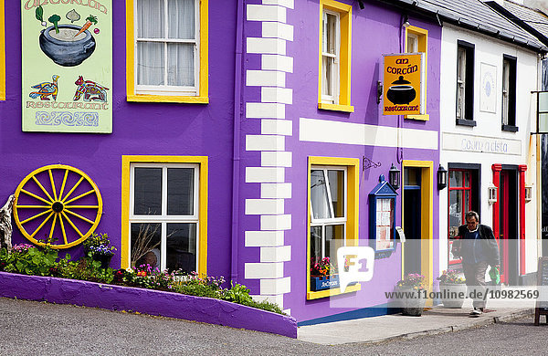 'A colourful shop on the corner and a pedestrian walking by; Waterville  County Kerry  Ireland'