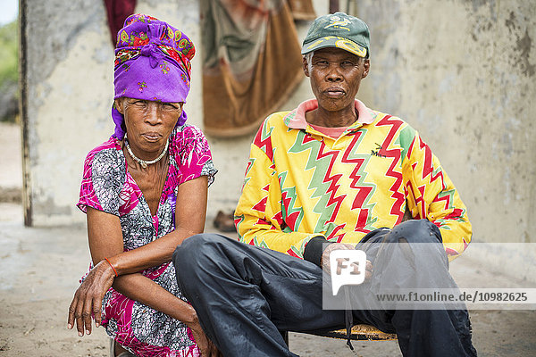 Mann und Frau sitzen zusammen und tragen helle  farbenfrohe Kleidung  San-Leute; Ghanzi  Botswana'.