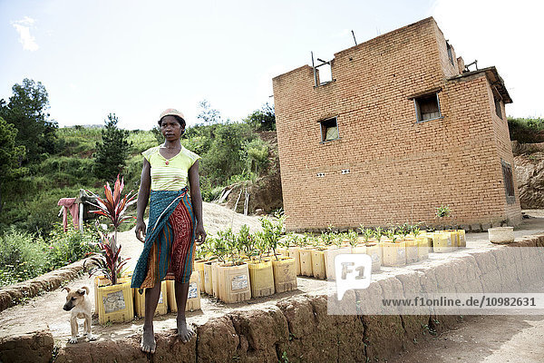 Junge Frau vor ihrem Haus und ihrem Containergarten; Madagaskar .