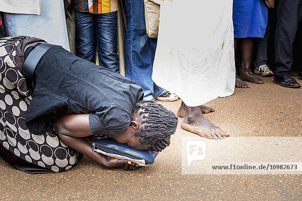 'A woman kneels on the street beside an actor reenacting Jesus Christ on Good Friday; Gulu  Uganda'
