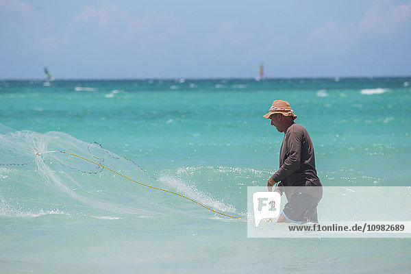 Ein kubanischer Fischer wirft an einem sonnigen Tag ein Netz im karibischen Meer aus  um Fische im blauen Wasser zu fangen; Varadero  Kuba'.