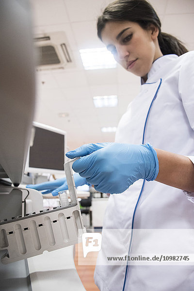 Laboratory technician in analytical laboratory putting samples in autoanalyzer