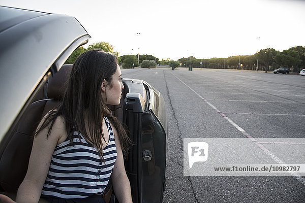 Young woman sitting in convertible watching something