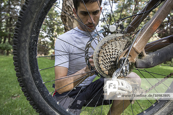 Mann beim Prüfen und Einstellen des Rades eines Mountainbikes