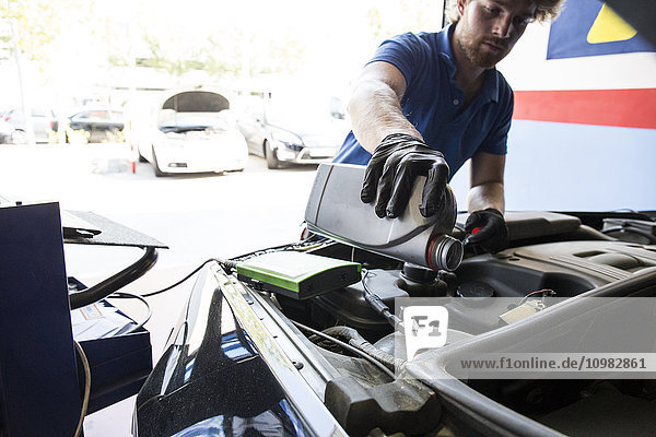 Mechanic refilling oil in a car