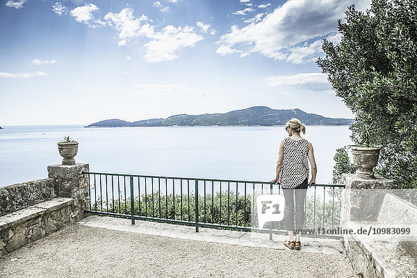 Croatia  Trsteno  back view of woman standing on a terrace looking to the sea