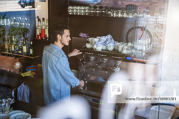 Junger Mann beim Kaffeezubereiten im Café
