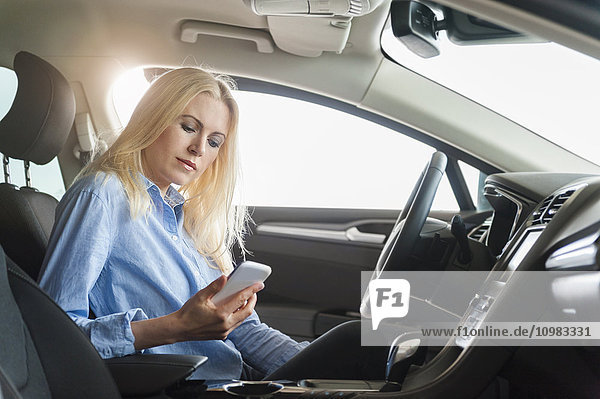 Woman in car looking on cell phone