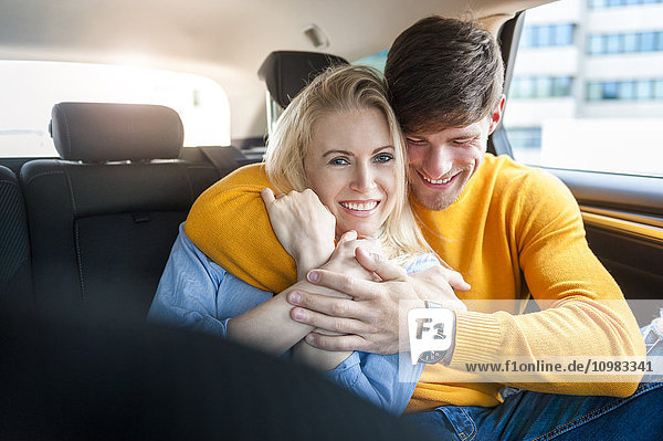 Smiling couple in love on back seat of a car
