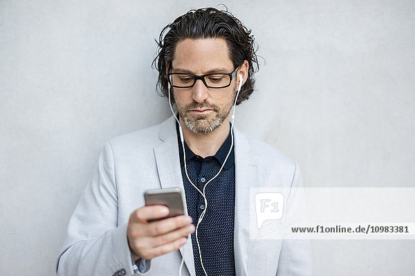 Businessman using smartphone with earphones