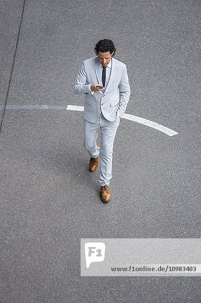 Walking Geschäftsmann mit Smartphone Kreuzung Straße beim Blick auf Handy