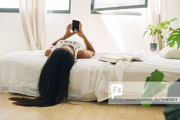 Junge Frau im Bett liegend mit dem Handy