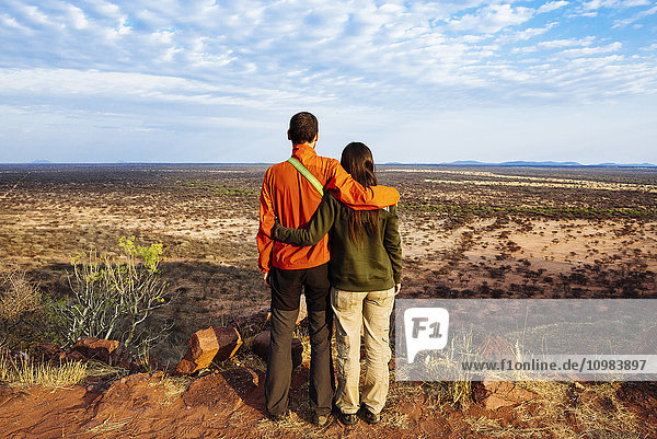 Namibia  embracing couple overlooking the vast plains in the african savannah from a natural viewpoint