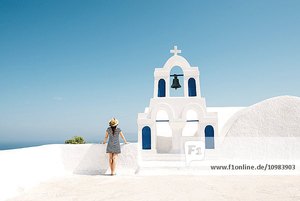 Griechenland,  Santorini,  Oia,  Rückansicht der Frau neben dem Glockenturm mit Blick auf das Meer