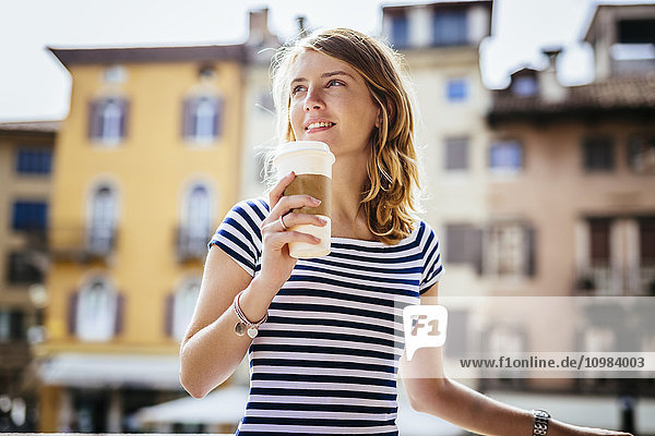 Italy  Udine  portrait of smiling young woman with coffee to go