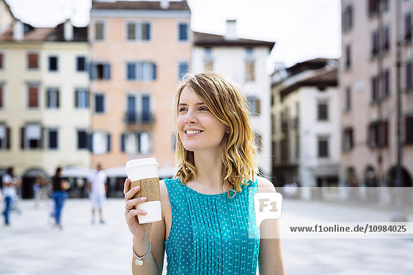 Porträt einer lächelnden jungen Frau mit Kaffee zum Mitnehmen