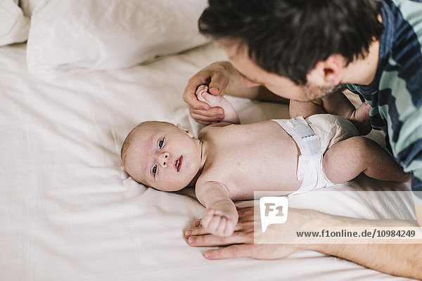 Father with baby boy lying on bed at home