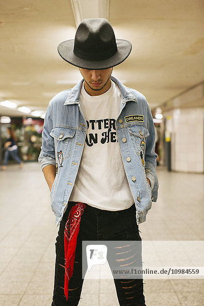 Modischer junger Mann mit Hut und Jeansjacke