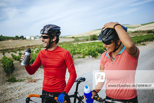 Spain  Andalusia  Jerez de la Frontera  couple of bikers drinking water on a rural road between vineyards