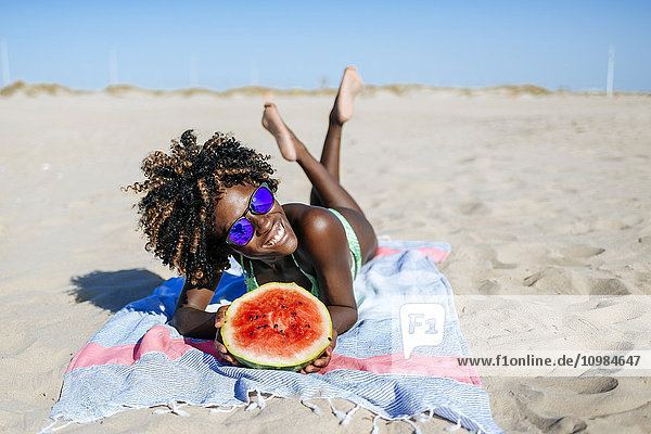 Glückliche junge Frau mit Wassermelone am Strand