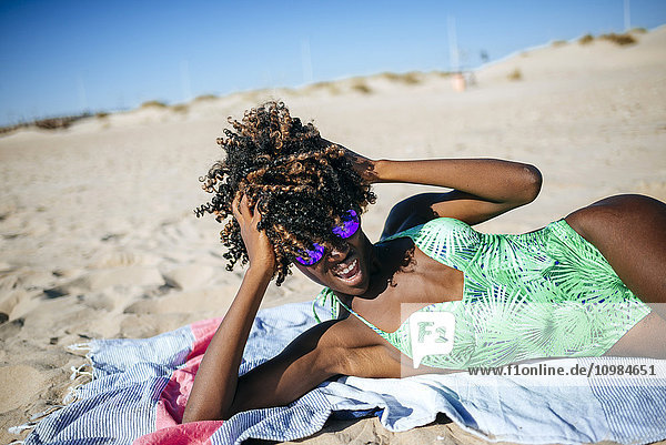 Junge Frau auf einem Handtuch am Strand liegend