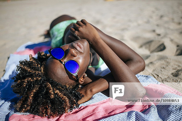 Junge Frau auf einem Handtuch am Strand liegend
