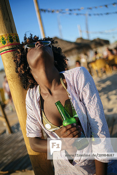 Junge Frau am Strand bei einer Flasche Bier entspannen