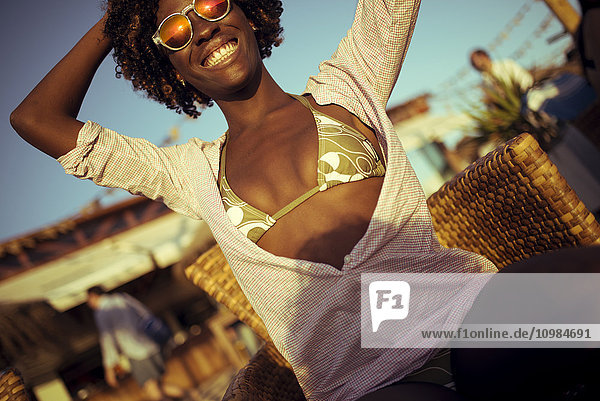 Lächelnde junge Frau an einer Strandbar