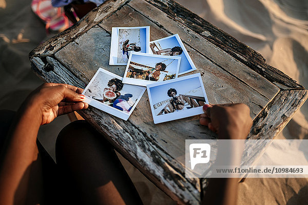 Frauenhände mit Sofortfotos auf einem Holztisch am Strand