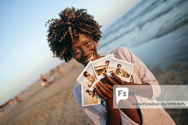 Junge Frau mit Sofortbildern am Strand