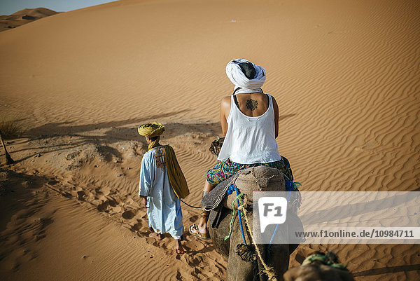 Frau auf einem Kamel in der Wüste mit Berberführerin