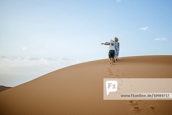 Berber man and woman tourist walking in the desert  pointing to the left