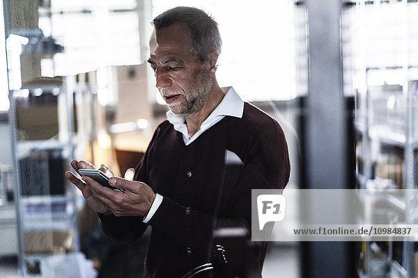 Mature man in a factory using cell phone