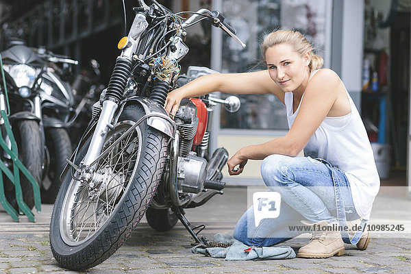 Porträt einer lächelnden jungen Frau neben dem Motorrad